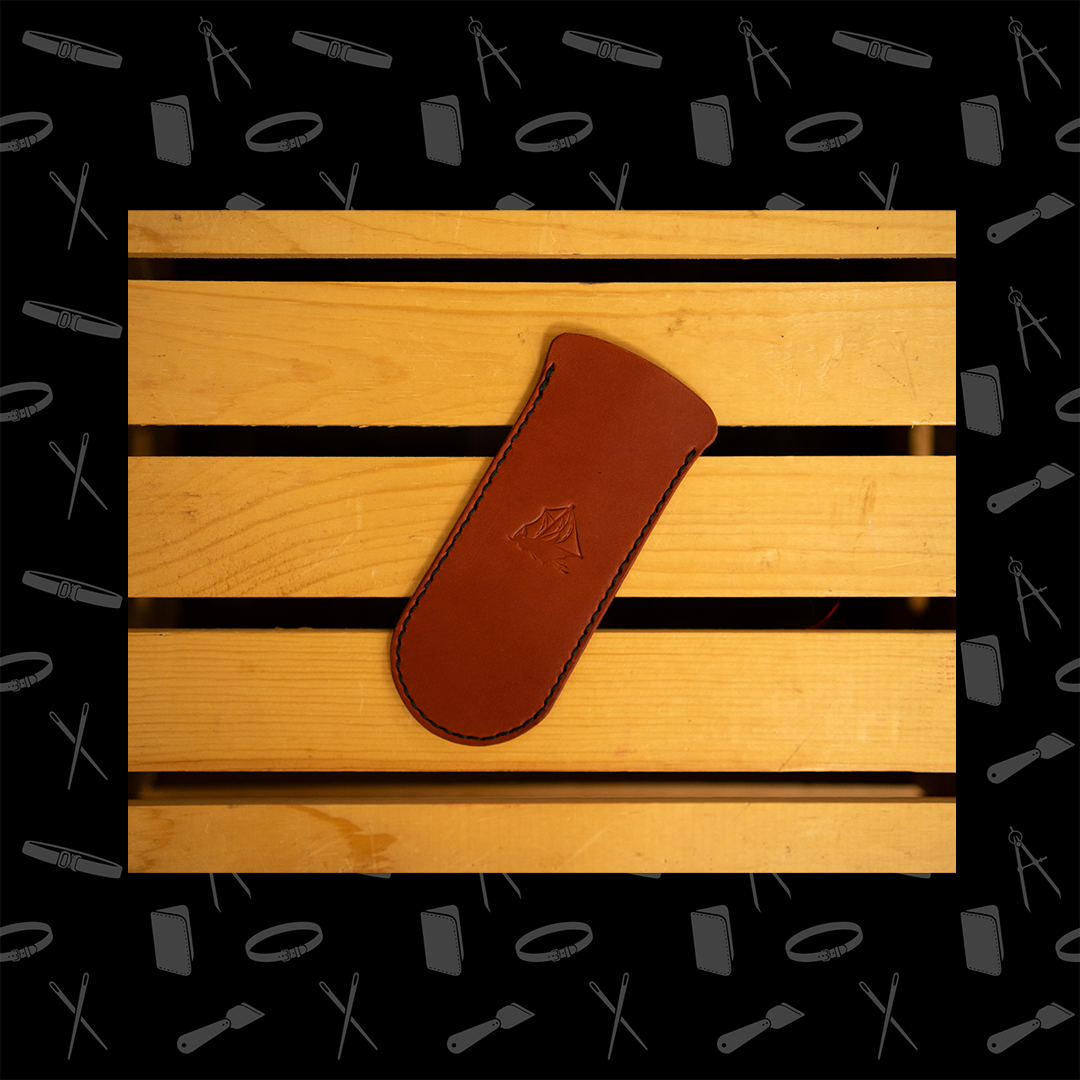 Brown leather skillet handle cover with a logo on a wooden surface