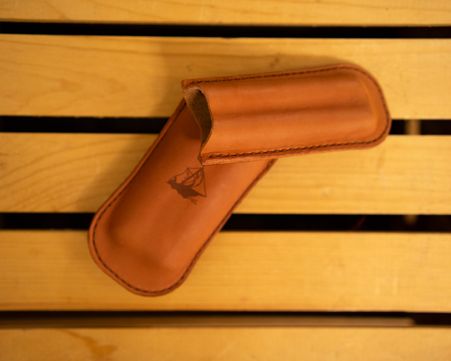 Leather cigar case with a logo on a wooden surface