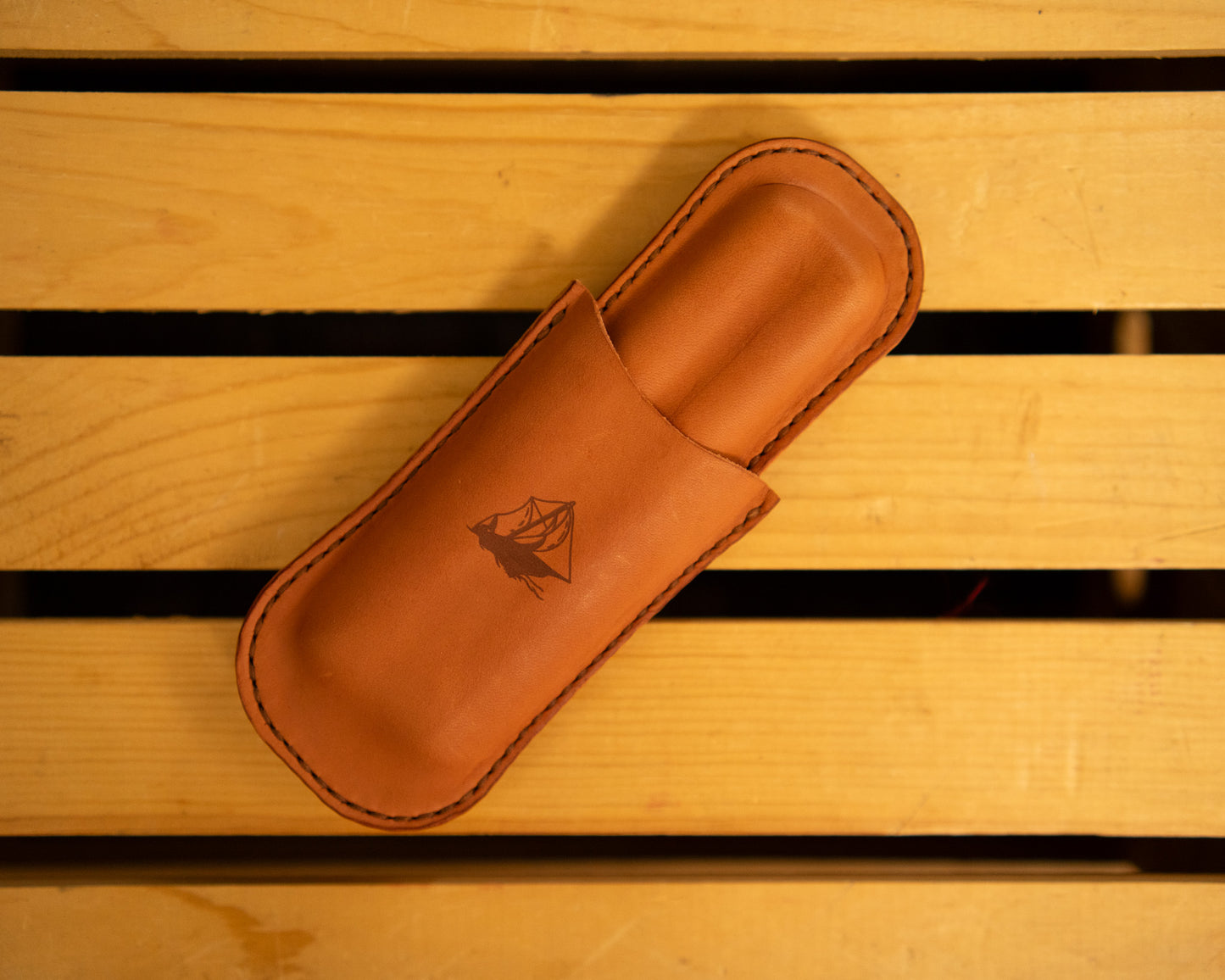 Leather cigar case with a logo on a wooden surface