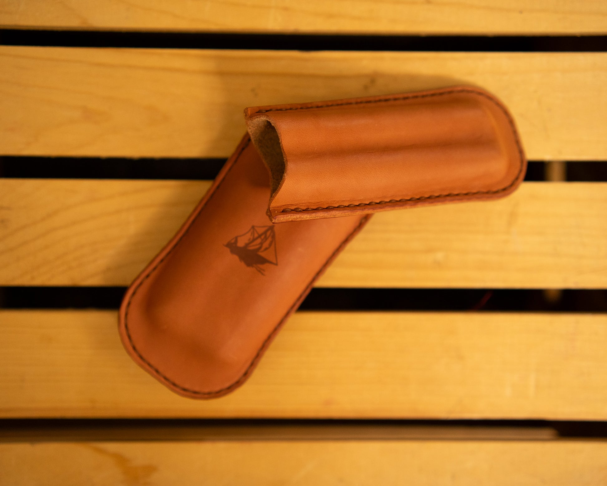 Leather cigar case with a logo on a wooden surface